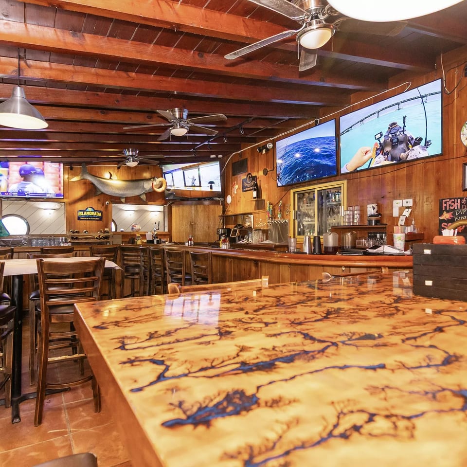 Rustic bar interior with wooden walls, ceiling, and a unique fractal-patterned bar top.