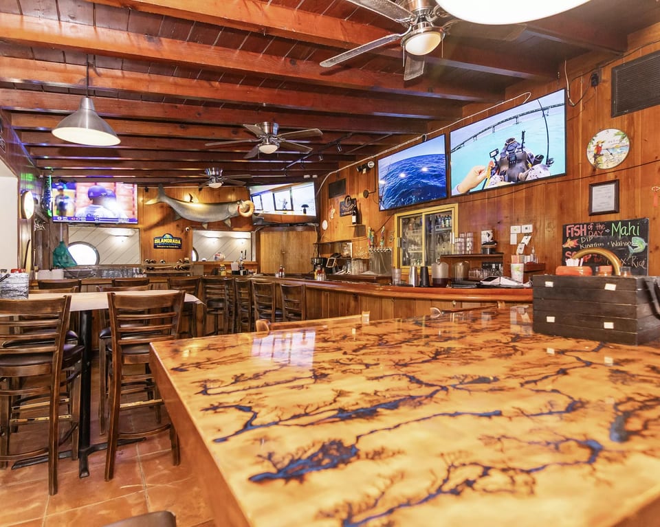 Rustic bar interior with wooden walls, ceiling, and a unique fractal-patterned bar top.
