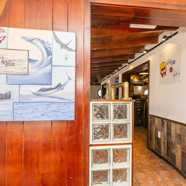A wooden wall with a fishing-themed painting next to an entryway with glass blocks and a tiled floor.